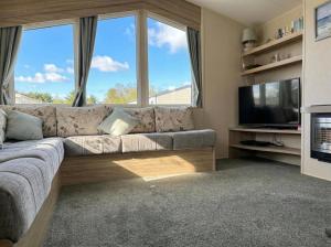 a living room with a couch and a television at Prime lakeside caravan at Haven Golden Sands in Mablethorpe