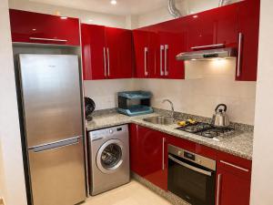 a kitchen with red cabinets and a stainless steel refrigerator at Appartement standing terrasse privative et piscine - Kariat Cabo in Cabo Negro