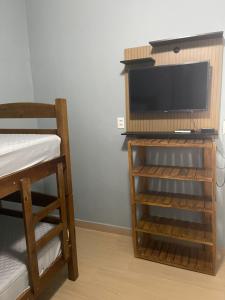 a room with a bed and a tv and a shelf at Ape Bianck's in Ilha Comprida