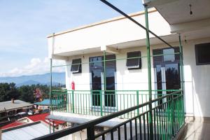 a balcony of a white building with green railing at Fido's Guesthouse in Ruhengeri +19 photos