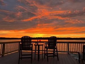 two chairs and a table on a deck with a sunset at Wake N Lake in Littleton