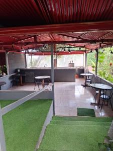 a covered patio with tables and green grass at ApartHotel Villa Pacande & Rooms in Alajuela