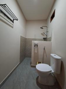 a bathroom with a white toilet in a room at Iza home stay in Senaru