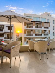 a patio with tables and chairs and an umbrella at Appartement standing terrasse privative et piscine - Kariat Cabo in Cabo Negro