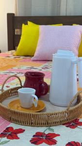 a tray with a tea kettle and a cup on a bed at Casa verde Recanto Doce lar in Gravatá