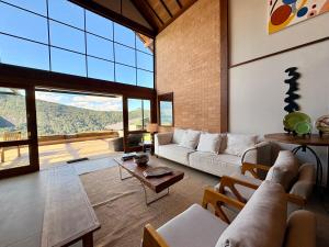 a living room with a couch and a table at Casa 02 Monte Boa Vista - Casa de 4 Suítes com Vista Deslumbrante in Teresópolis
