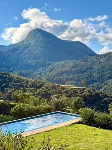 a swimming pool with a mountain in the background at Casa 02 Monte Boa Vista - Casa de 4 Suítes com Vista Deslumbrante in Teresópolis