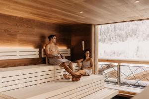 a man and a woman sitting on a bed at Hofgut Wagrain Apartment & Lifestyle Resort in Wagrain