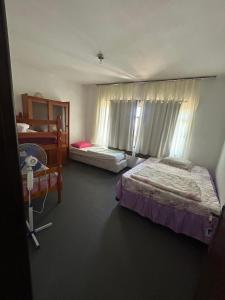 a bedroom with two beds and two windows at Pousada Ponta Grossa in Ponta Grossa