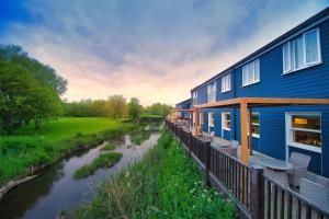 a house with a deck next to a river at The Bridge House; BW Signature Collection in Ferndown