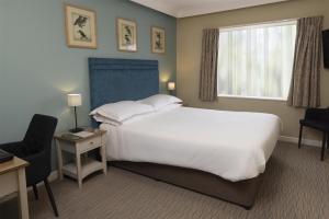 a bedroom with a large white bed and a window at The Bridge House; BW Signature Collection in Ferndown