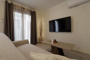 a living room with a couch and a tv and a table at Hidden Petra Luxury Suites 2 in Ialysos