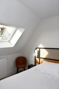 a bedroom with a bed and a chair and a window at Hotel Moderne in Arras