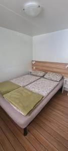 a bed in a room with a wooden floor at Mobilheim Coco in Biograd na Moru