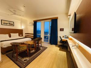 a hotel room with a bed and a table and chairs at Golden Pent House in Lucknow