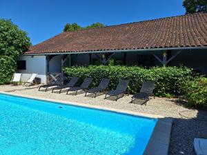 a pool with chairs next to a house at Les Renaudières Chalais in Chalais