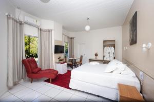 a bedroom with a white bed and a red chair at Hotel SPA Paraíso in Cruzeiro do Sul