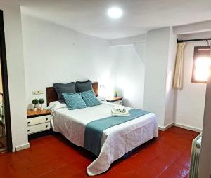 a bedroom with a large bed with blue pillows at Casa cubo in Alhama de Granada