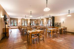 a restaurant with wooden tables and chairs and windows at Hotel Toč in Lipova Lazne
