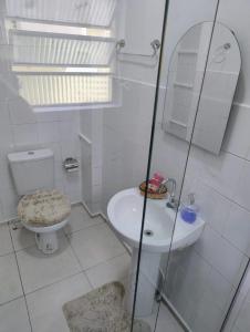 a white bathroom with a toilet and a sink at Edícula Planalto in Manaus