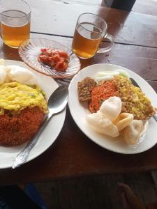 a table with two plates of food and two glasses of beer at RAMMANG-RAMMANG HOUSE in Maros