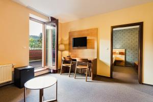 a hotel room with a table and chairs and a television at Hotel Toč in Lipova Lazne