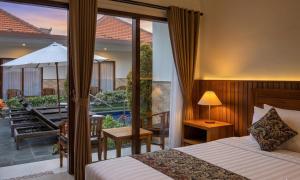 a bedroom with a bed and a balcony with a patio at Cening Ayu Sanur in Sanur