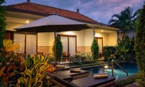 a house with an umbrella and a swimming pool at Cening Ayu Sanur in Sanur +11 photos
