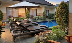a patio with an umbrella and chairs and a pool at Cening Ayu Sanur in Sanur