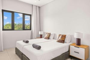 two beds in a white room with a window at Penthouse Kyo - Private Rooftop & Jacuzzi in Grand-Baie +30 photos