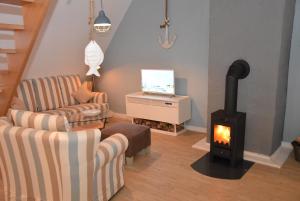 a living room with a wood stove and a couch at Dannauer Reetkate - Wiesenblick in Oldenburg in Holstein
