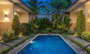 a swimming pool in a garden with trees and plants at Cening Ayu Sanur in Sanur