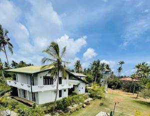 a white house with palm trees in front of it at The Lark Resort , Induruwa in Induruwa