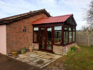 a greenhouse with a red roof on a brick house at The Catkins, Grove flock farm in Diss