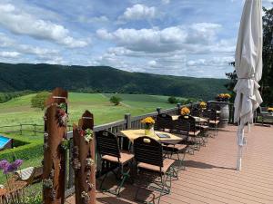 a deck with tables and chairs with a view of a golf course at Ferienhof Oldach in Bacharach +22 photos