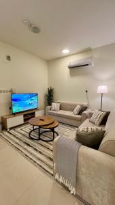 a living room with a couch and a flat screen tv at اكنان للشقق المفروشة in Buraydah