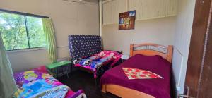 a room with two beds and a chair and a window at Cabaña con piscina y vista al lago in San Bernardino