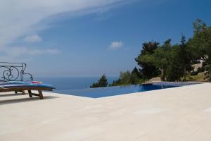 a bench sitting on a patio next to a swimming pool at Erimitis View Villa in Magaziá