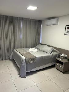 a bedroom with a bed and a table with a night stand at Flat Ilha do Leite in Recife