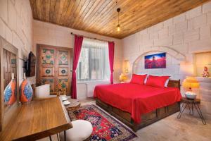 a bedroom with a red bed in a room at Megaron Cave Hotel Cappadocia in Ortahisar