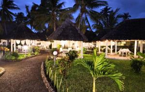 a resort with tables and chairs and palm trees at night at Ascot Watamu Resort in Watamu