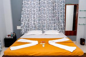 a bedroom with a bed with an orange blanket at Jageshwari Executive in Kolhapur