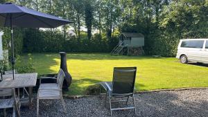 a table and chairs and an umbrella in a yard at Serenity Cottage in Newpark