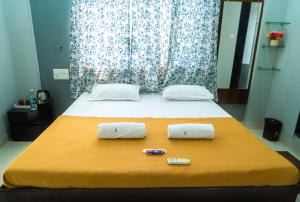 a bedroom with a bed with two pillows on it at Jageshwari Executive in Kolhapur