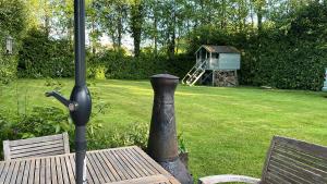 a wooden table with an umbrella and a bird house at Serenity Cottage in Newpark +10 photos