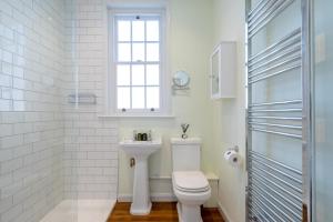 a white bathroom with a toilet and a sink at Stable Yard Cottage in Osmaston