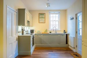 a kitchen with green cabinets and a sink and a window at Stable Yard Cottage in Osmaston