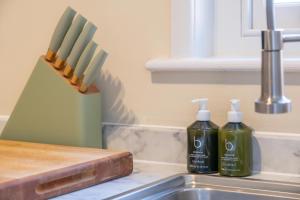 two bottles of detergent sitting next to a kitchen sink at Stable Yard Cottage in Osmaston