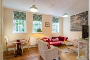 a living room with a red couch and chairs at Stable Yard Cottage in Osmaston +5 photos