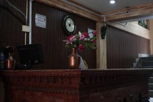 a counter with a vase of flowers on it with a clock at Hotel Terracotta in Bhaktapur